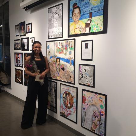 the artist standing in front of many paintings 